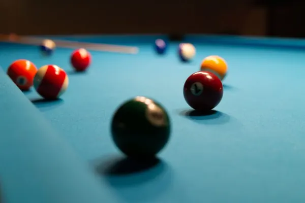 Nahaufnahme roter und dunkler Billardkugeln auf blauem Tuch